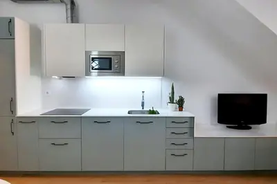 a white kitchen with a sink and a tv at Acogedor apartamento con entrada independiente in Barcelona