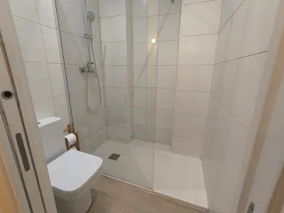 a white bathroom with a shower and a toilet at Acogedor apartamento con entrada independiente in Barcelona