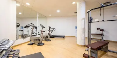 a gym with treadmills and ellipticals in a room at Ilunion Auditori in Barcelona