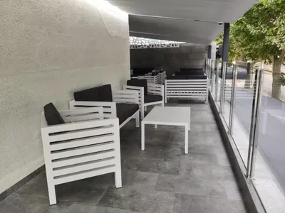 a restaurant with white chairs and tables and benches at Hotel Internacional in Calella