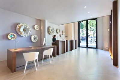 a living room with a table and chairs and a person at Hotel Condes de Barcelona in Barcelona