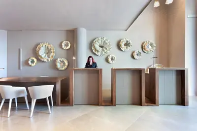 a woman standing at a counter in a room with plates on the wall at Hotel Condes de Barcelona in Barcelona