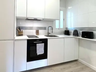 a kitchen with white cabinets and a black dishwasher at Click&Flat Rizal in Barcelona
