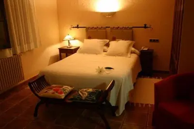 a bedroom with a white bed and a chair at Hotel Golf Can Rafel in Corbera de Llobregat