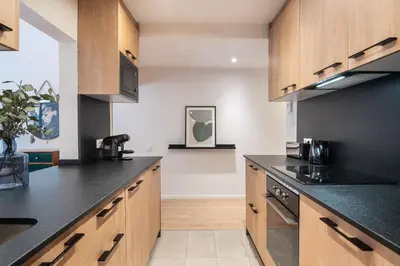 a kitchen with black counter tops and wooden cabinets at Design and comfort in the trendy neighborhood in Barcelona