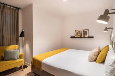 a bedroom with a bed and a yellow chair at Design and comfort in the trendy neighborhood in Barcelona