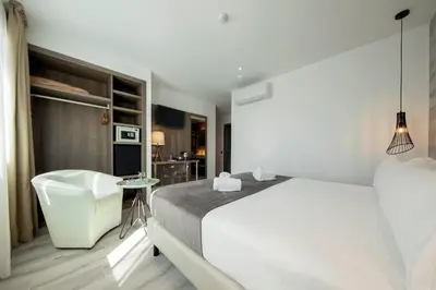 a white bedroom with a bed and a chair at Hotel Oasis in Barcelona
