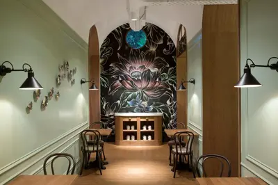 a restaurant with tables and chairs and a wall with a mural at Petit Palace Boqueria Garden in Barcelona