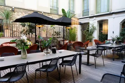 a patio with tables and chairs and an umbrella at Petit Palace Boqueria Garden in Barcelona