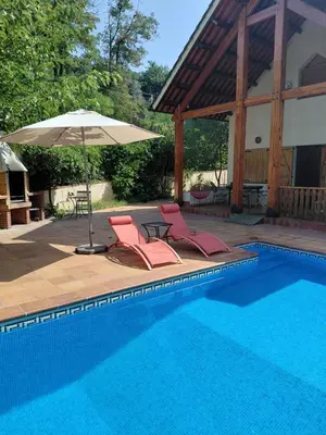 a swimming pool with two chairs and an umbrella at Chalet Entre Parques Naturales in Vallgorguina