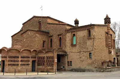 an old brick building with a flag on top of it at Precioso Piso Barcelona in Santa Coloma de Cervelló