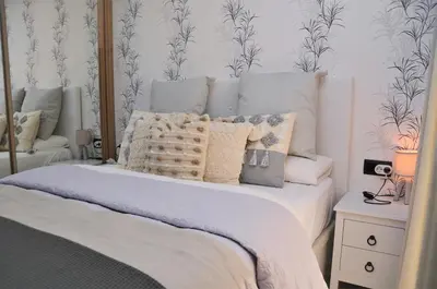 a bedroom with a bed with white sheets and wallpaper at Apartamento Sofia in Pineda de Mar