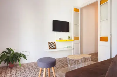 a living room with a couch and two stools and a tv at Sagrada Familia V by Enjoy Apartments in Barcelona