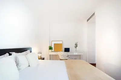 a bedroom with a large white bed with a chair at Enjoy Apartments Maria II in Barcelona