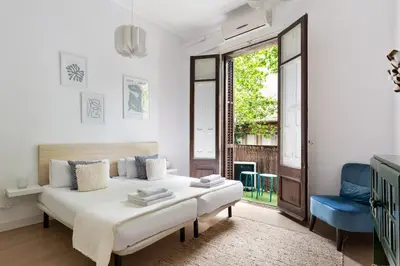 a white bedroom with a bed and a blue chair at Sagrada Familia II by Enjoy Apartments in Barcelona