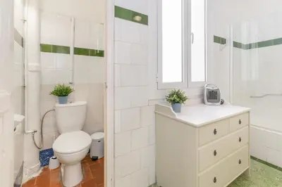 a white bathroom with a toilet and a sink at Vistamar 1: Primera línea de mar con encanto in Sitges