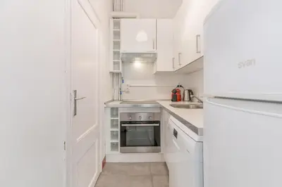 a white kitchen with white cabinets and a refrigerator at Vistamar 1: Primera línea de mar con encanto in Sitges