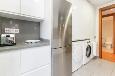 a kitchen with a refrigerator and a washer and dryer at Sant Sebastià Moderno apartamento a 100 metros de la playa in Sitges