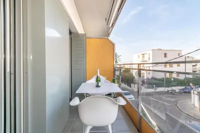 a balcony with a white table and a white chair at Sant Sebastià Moderno apartamento a 100 metros de la playa in Sitges