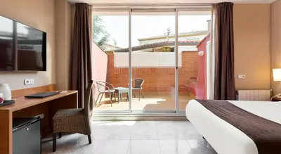 a hotel room with a bed and a desk and a window at PARK SEDO Aparthotel in Rubí