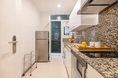 a kitchen with white cabinets and a stainless steel refrigerator at Apartments Sata Sagrada Familia Area in Barcelona