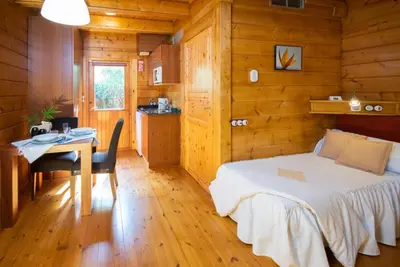 a bedroom with a bed and a table and a kitchen at Hotel Somlom - ECO Friendly Montseny in Sant Esteve de Palautordera