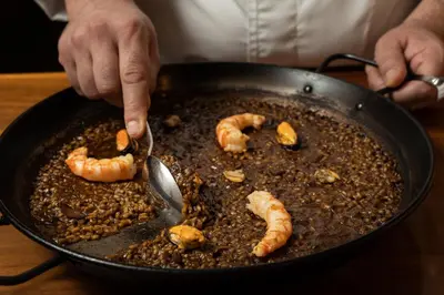 a person is cooking food in a pan with shrimp at Catalonia Ramblas 4* Sup in Barcelona