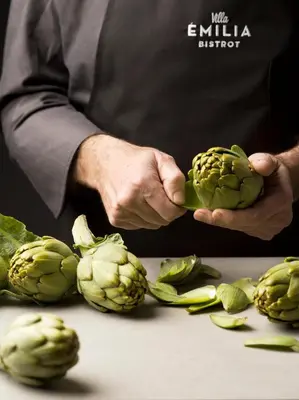 a man holding a head of artichokes on a table at Hotel Villa Emilia in Barcelona
