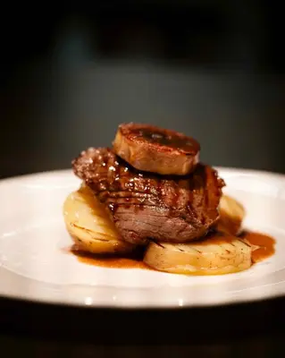 a pile of meat and potatoes on a white plate at Hotel Villa Emilia in Barcelona