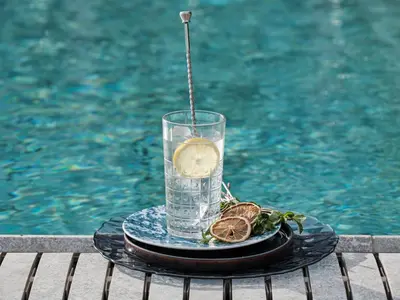 a glass of water on a table next to a pool at Qgat Restaurant Events & Hotel in Sant Cugat del Vallès