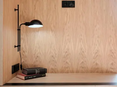 a lamp and books on a shelf with a wall at Qgat Restaurant Events & Hotel in Sant Cugat del Vallès