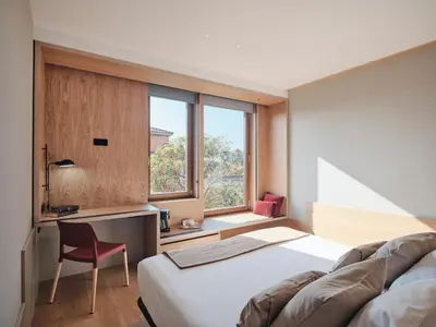a bedroom with a bed and a desk and a window at Qgat Restaurant Events & Hotel in Sant Cugat del Vallès