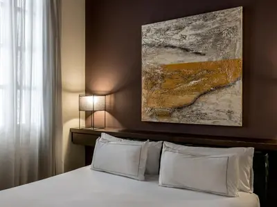 a bedroom with a bed with a painting above it at Mercer House Bòria BCN in Barcelona