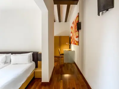 a bedroom with a bed with white walls and wooden floors at Mercer House Bòria BCN in Barcelona