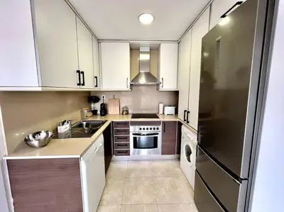 a kitchen with white cabinets and a stainless steel refrigerator at Acogedor apartamento entero in Terrassa