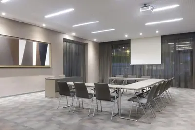 a conference room with a table and chairs and a projection screen at AC Hotel San Cugat by Marriott in Sant Cugat del Vallès