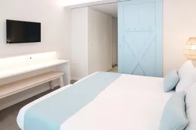a bedroom with a white bed and a tv on a wall at KAKTUS Hotel Kaktus Playa in Calella