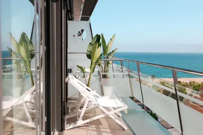 a balcony with a white chair and the ocean at KAKTUS Hotel Kaktus Playa in Calella