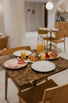 a table with plates of food and glasses of orange juice at Hotel Petit Luxe in Terrassa
