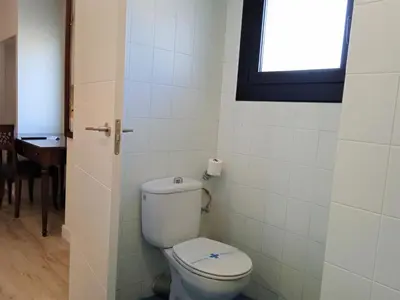 a bathroom with a toilet with a window and a table at Hotel 153 in Castelldefels