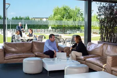 a group of people sitting on a couch with a laptop at BAH Barcelona Airport Hotel in El Prat de Llobregat
