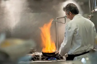 a chef cooking food in a wok with flames at BAH Barcelona Airport Hotel in El Prat de Llobregat