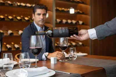 a man pouring a glass of wine at a table at BAH Barcelona Airport Hotel in El Prat de Llobregat