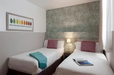 two beds in a hotel room with a book on the bed at MH Apartments S. Familia in Barcelona