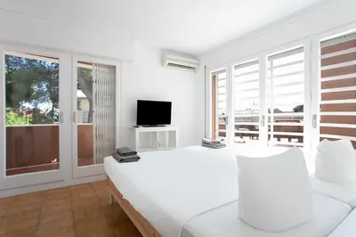 a white bedroom with a bed and a television at Canela Homes COSTA CASA AILA in Castelldefels