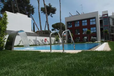 a swimming pool with two water fountains in front of a building at Apartamentos Royal Marina Gardens in Castelldefels