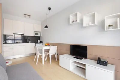 a living room with a white kitchen and a table with chairs at Apartamentos Royal Marina Gardens in Castelldefels