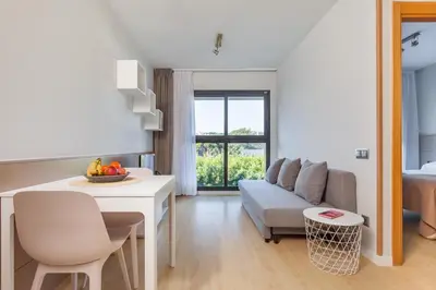 a kitchen and living room with a table and a couch at Apartamentos Royal Marina Gardens in Castelldefels