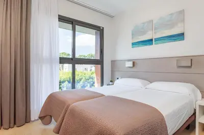 a bedroom with two beds and a large window at Apartamentos Royal Marina Gardens in Castelldefels