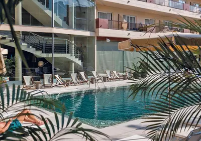 a swimming pool with lounge chairs and a building at AQUA Hotel Promenade & Spa 4Sup in Pineda de Mar